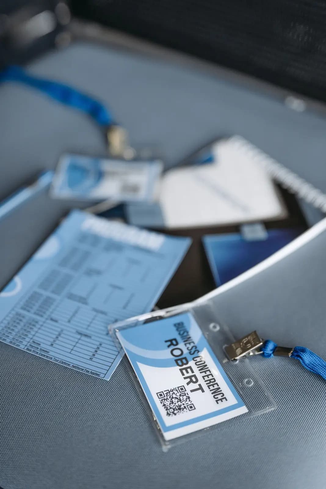 A conference badge with a QR code lies on a table beside a program.
