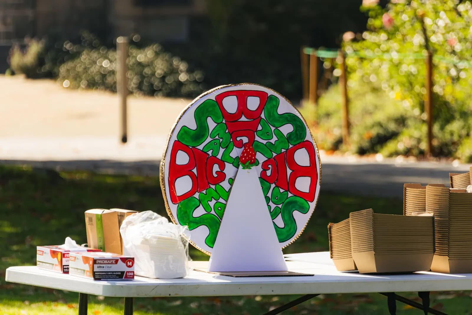 A hand-painted prize wheel on a folding table at an outdoor event.