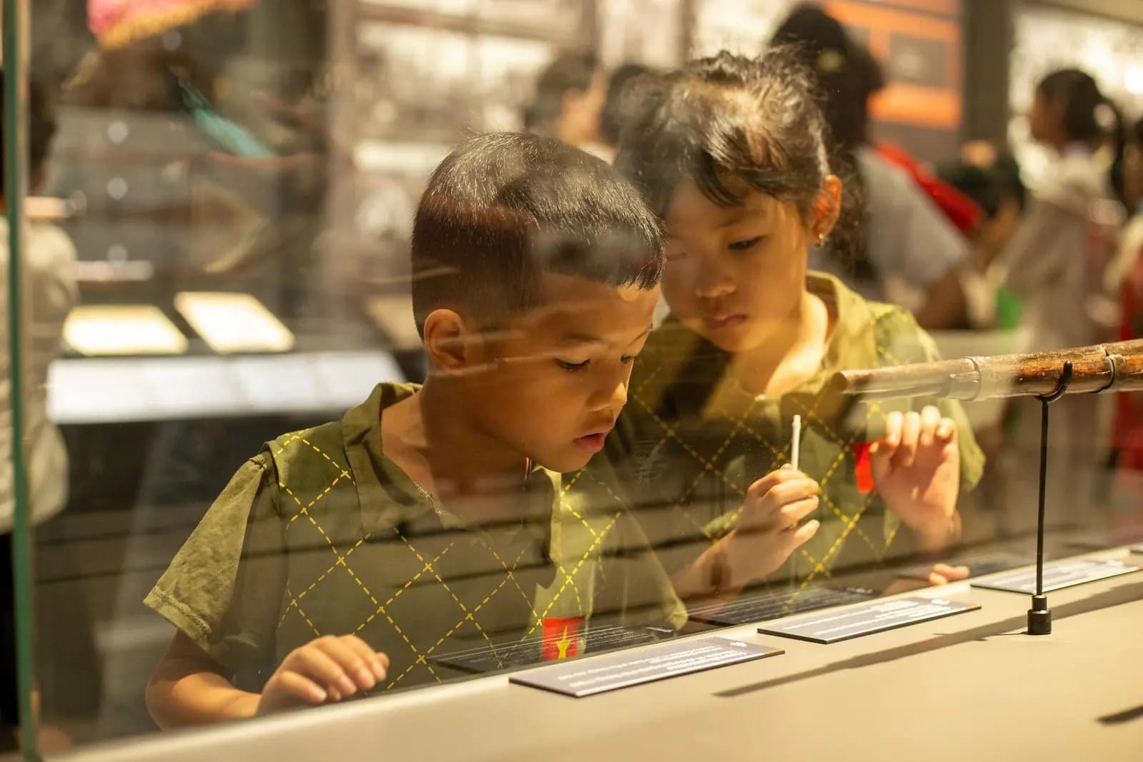Two children lean in at a glass display case in a museum, absorbed in what is inside.