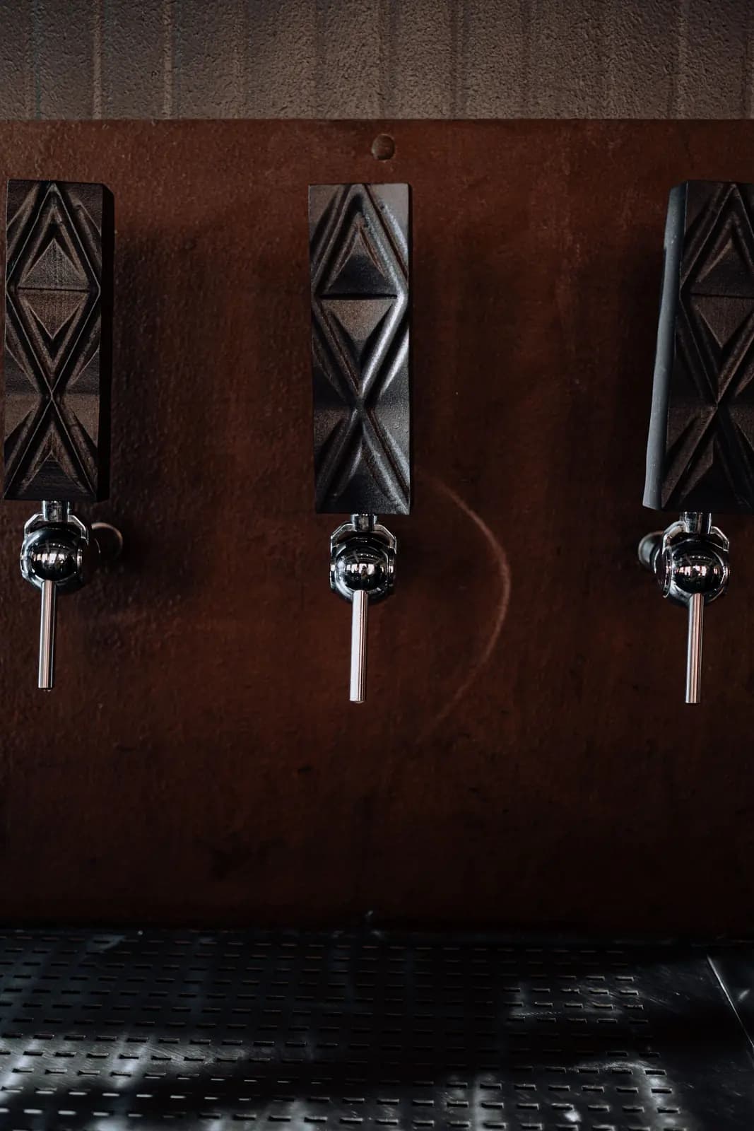 Three carved tap handles on a dark wall.