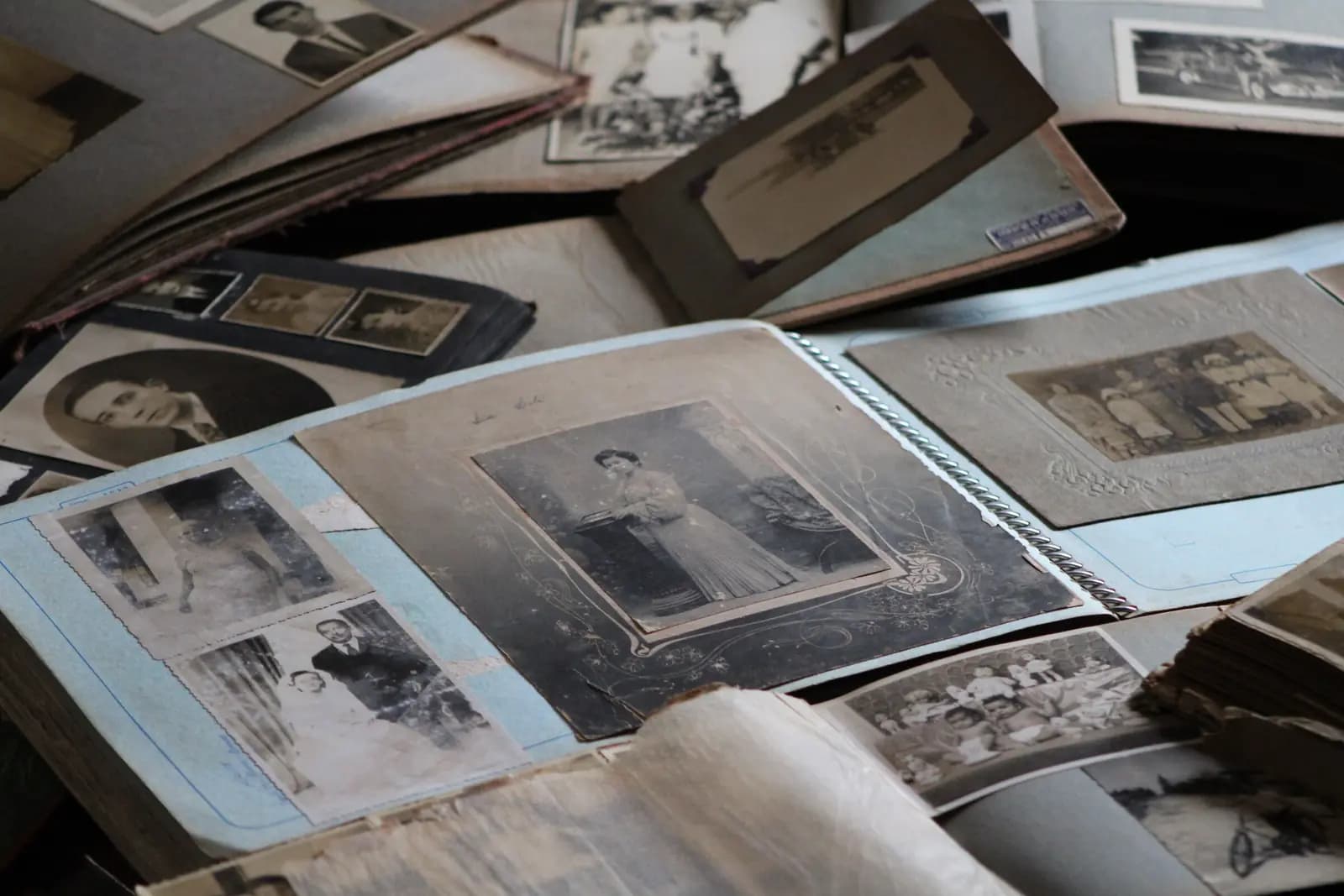 An old family photo album lying open among loose black-and-white prints.