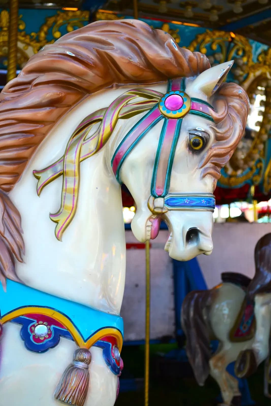 A white carousel horse with a painted bridle, seen head-on.