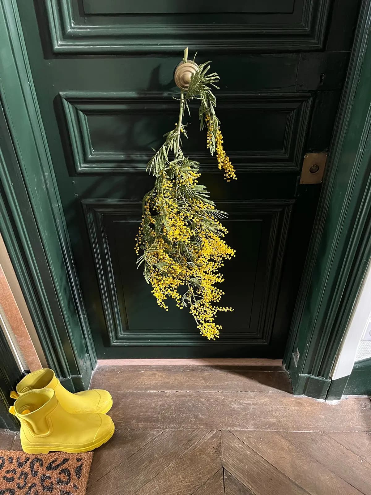 A pair of yellow rain boots by a front door.