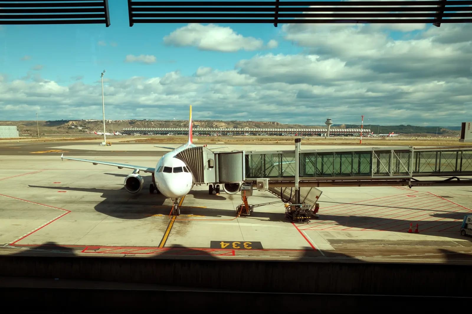 A plane parked at the gate seen through a terminal window.
